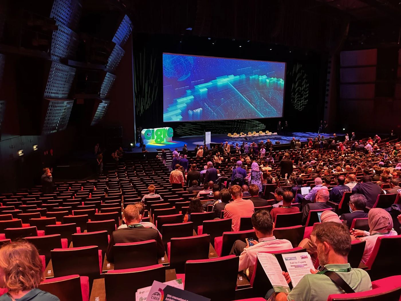 Volles Plenum vor einer großen Leinwand